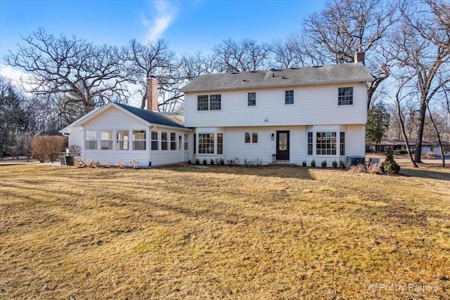 rear view of property with a chimney and a lawn