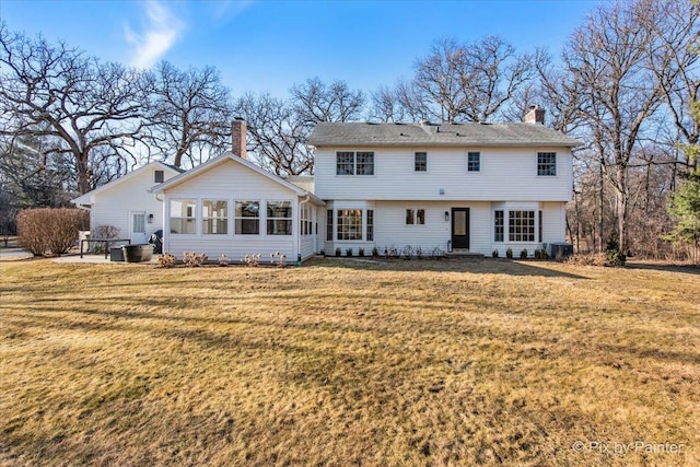 view of front of home with a front yard, a chimney, and central air condition unit