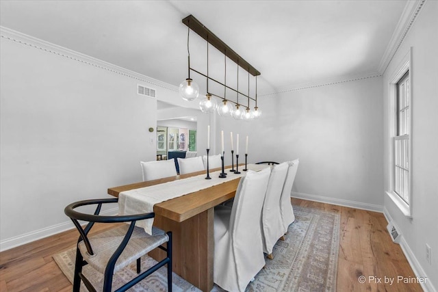 dining room with wood finished floors, visible vents, and baseboards