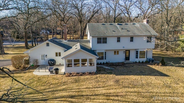 rear view of property featuring a patio area, a sunroom, and a lawn