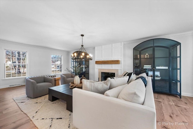 living area featuring a chandelier, crown molding, light wood-style floors, and baseboards