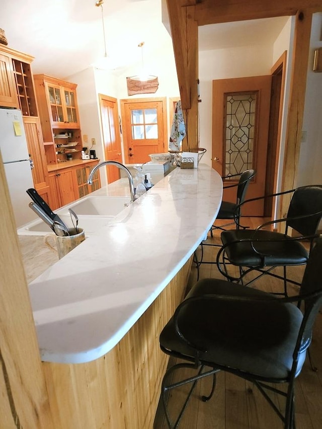 bar with wood finished floors, a sink, freestanding refrigerator, and decorative light fixtures