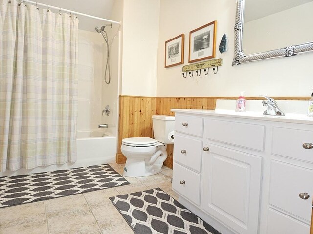 full bath with wooden walls, toilet, a wainscoted wall, shower / bath combination with curtain, and vanity