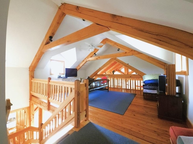 additional living space with ceiling fan, vaulted ceiling with beams, and wood finished floors