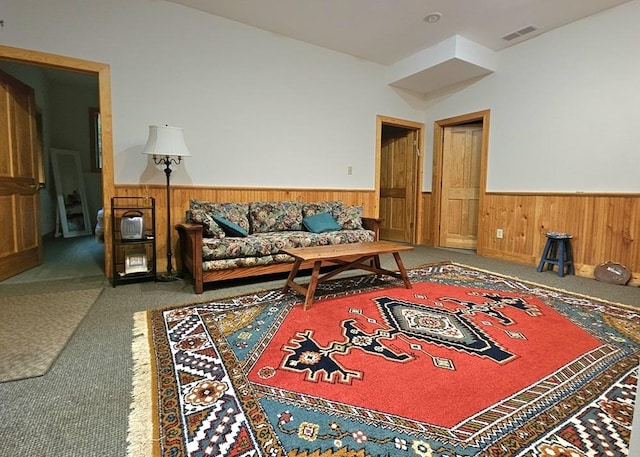 living room featuring wooden walls, wainscoting, visible vents, and carpet flooring