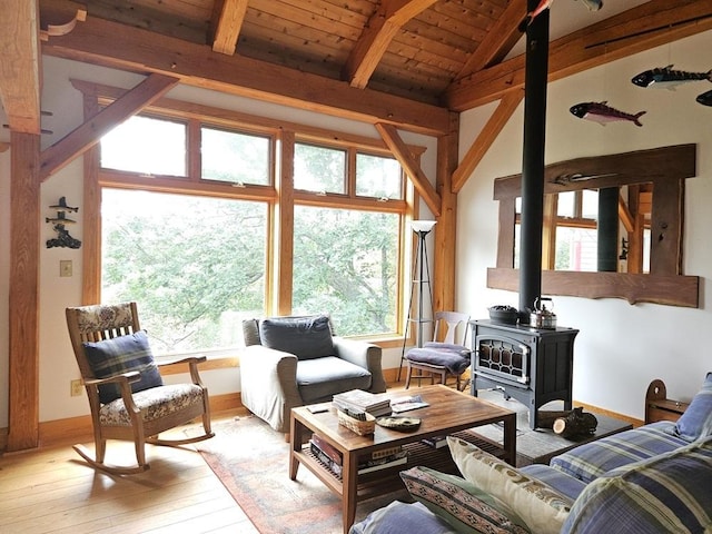 living room featuring light wood finished floors, baseboards, wooden ceiling, a wood stove, and vaulted ceiling with beams