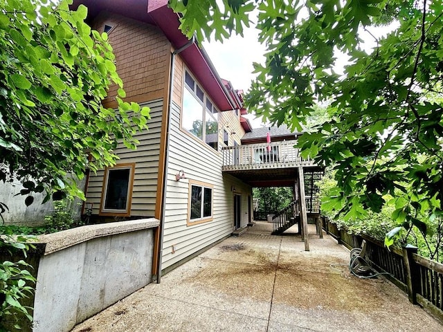 view of side of property with fence, stairway, a deck, and a patio