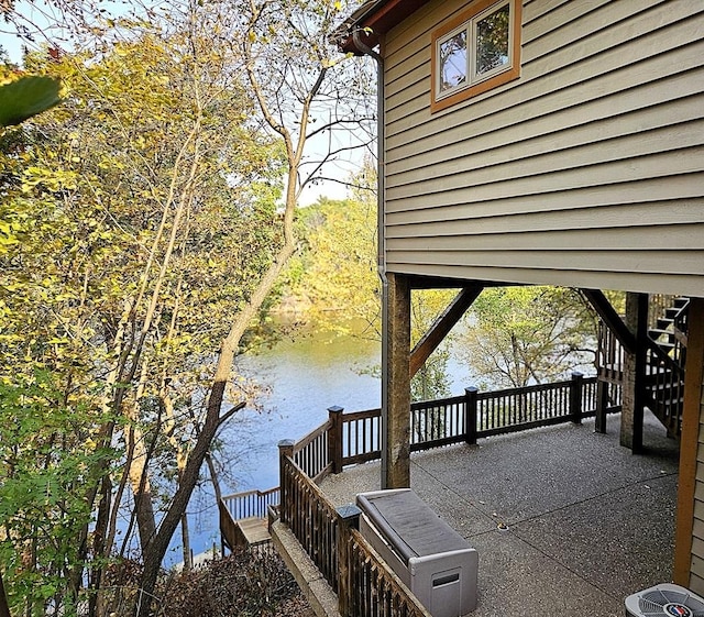 exterior space with a water view, stairway, and cooling unit