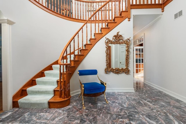 stairway with a towering ceiling, marble finish floor, baseboards, and visible vents