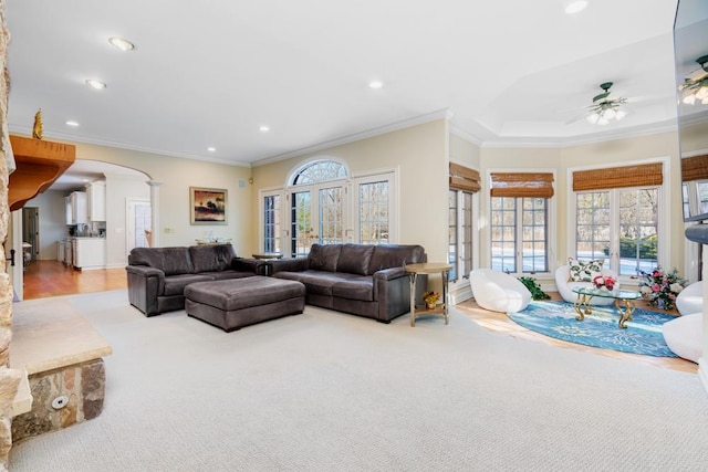 carpeted living area with ornamental molding, arched walkways, a ceiling fan, and recessed lighting