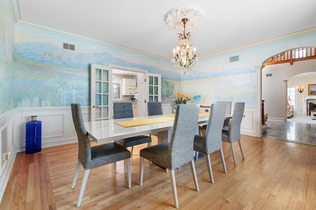 dining room with light wood finished floors, visible vents, arched walkways, and a chandelier