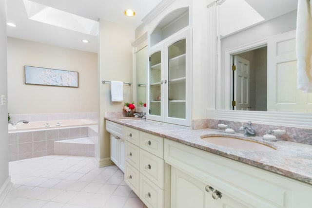 full bathroom featuring tile patterned flooring, a garden tub, a sink, and double vanity