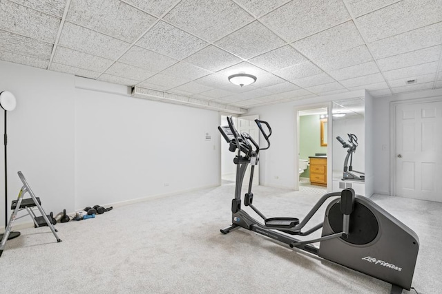 exercise room featuring a paneled ceiling and baseboards