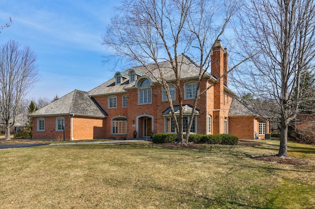 view of front of house with central air condition unit, a front yard, a chimney, and brick siding