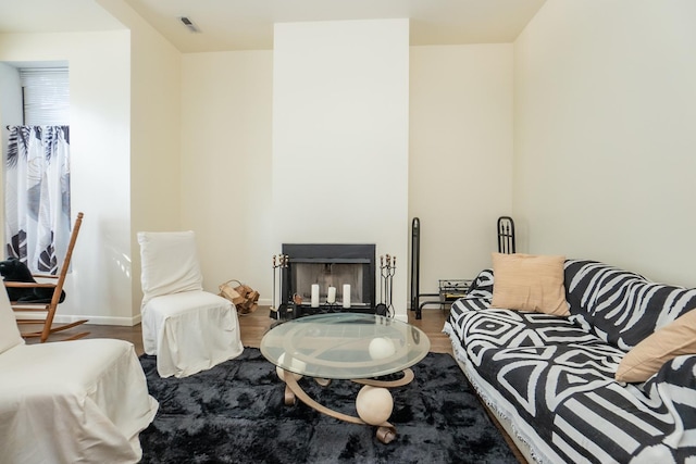 living room featuring visible vents, a fireplace, baseboards, and wood finished floors