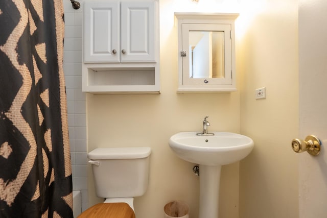 full bath featuring a shower with shower curtain, a sink, and toilet