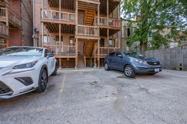 exterior space featuring uncovered parking, stairway, and fence