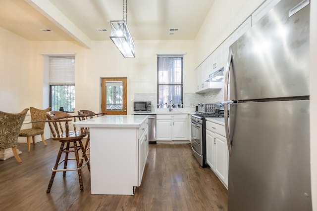 kitchen with stainless steel appliances, light countertops, white cabinetry, and under cabinet range hood