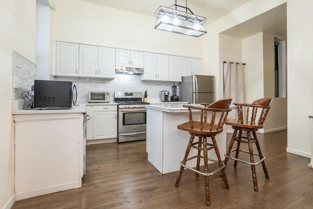 kitchen with white cabinets, a kitchen island, a breakfast bar area, stainless steel appliances, and under cabinet range hood