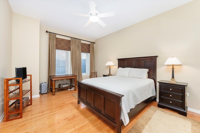 bedroom with light wood-style flooring, a ceiling fan, and baseboards