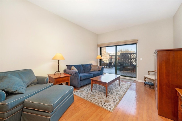 living area featuring light wood finished floors, baseboards, and lofted ceiling