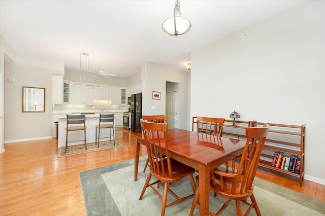 dining room featuring baseboards, light wood-type flooring, and ceiling fan