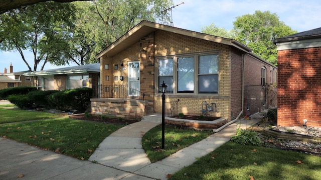 bungalow-style home featuring brick siding and a front lawn