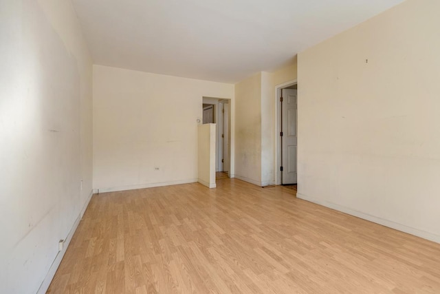 unfurnished room with light wood-type flooring and baseboards