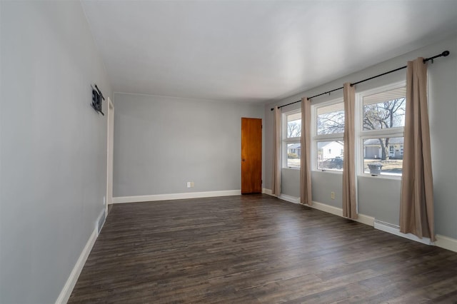 unfurnished room featuring baseboards and dark wood-style flooring