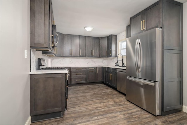 kitchen with decorative backsplash, appliances with stainless steel finishes, dark wood-style flooring, and light countertops