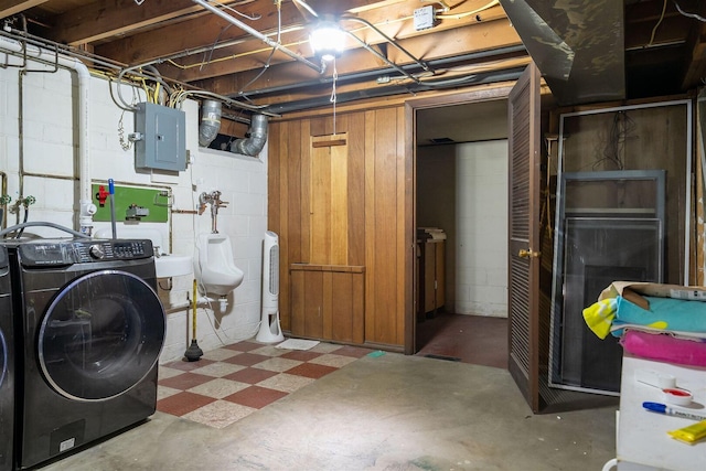 unfinished basement featuring electric panel, tile patterned floors, and washing machine and clothes dryer