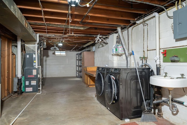 below grade area with electric panel, heating unit, and washing machine and dryer