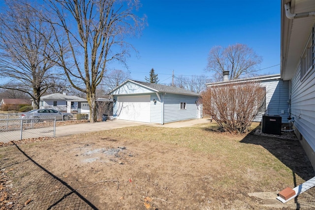 exterior space featuring central AC unit, fence, concrete driveway, an outdoor structure, and a detached garage