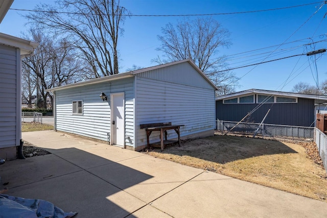 view of outdoor structure featuring an outbuilding, fence, and driveway