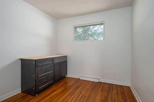 empty room with baseboards, baseboard heating, and dark wood finished floors