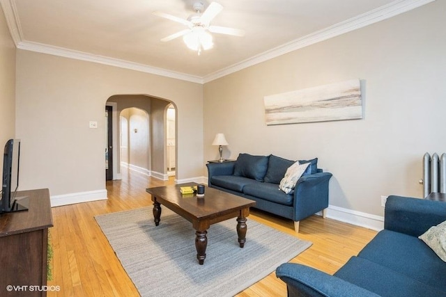 living area with light wood-style flooring, crown molding, arched walkways, and baseboards