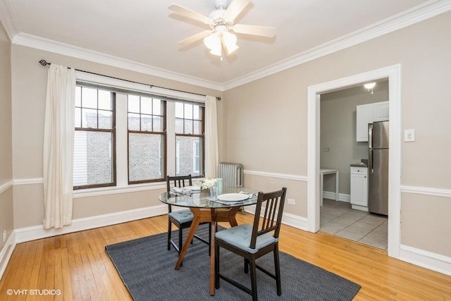 dining area with light wood finished floors, baseboards, and crown molding