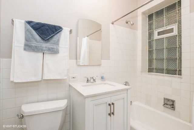 bathroom with shower / bathtub combination with curtain, tile walls, toilet, and vanity