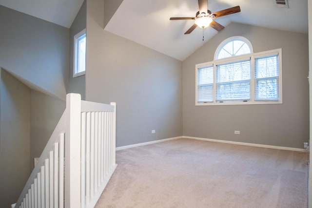 empty room featuring lofted ceiling, light colored carpet, visible vents, ceiling fan, and baseboards