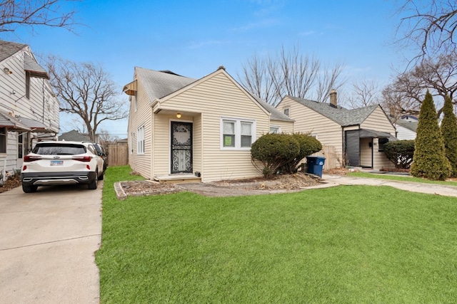 bungalow with driveway, a shingled roof, fence, and a front lawn