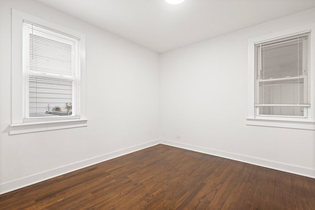 spare room featuring baseboards and dark wood-type flooring