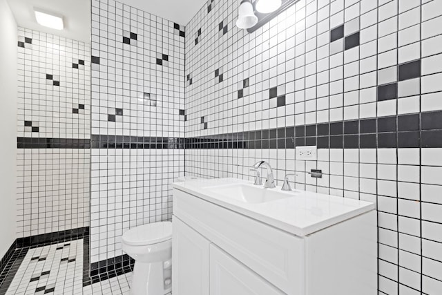 bathroom with toilet, vanity, tile walls, and tiled shower