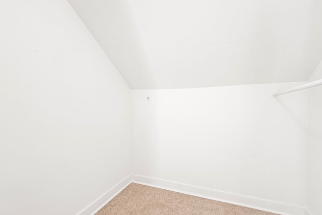 walk in closet featuring light carpet and vaulted ceiling