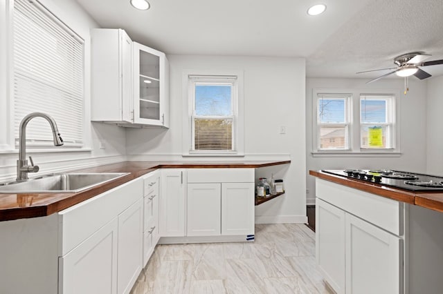 kitchen featuring a wealth of natural light, butcher block counters, black electric stovetop, and a sink