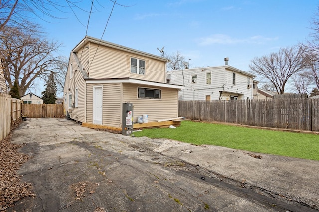 rear view of property with a patio area, gas water heater, a fenced backyard, and a yard