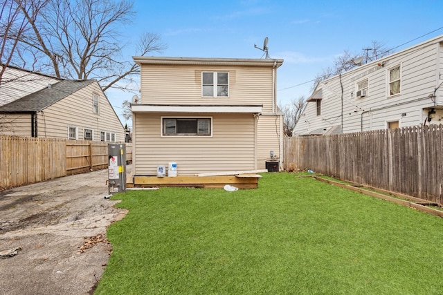 back of property with a fenced backyard, a yard, a deck, and water heater