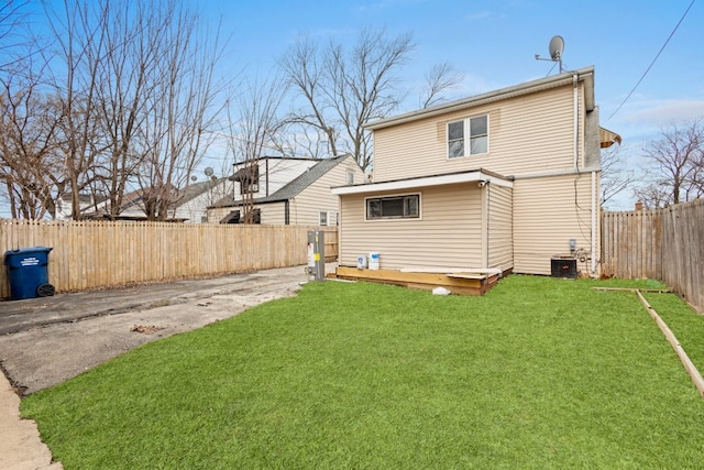 rear view of house with a fenced backyard, central AC, a deck, and a lawn