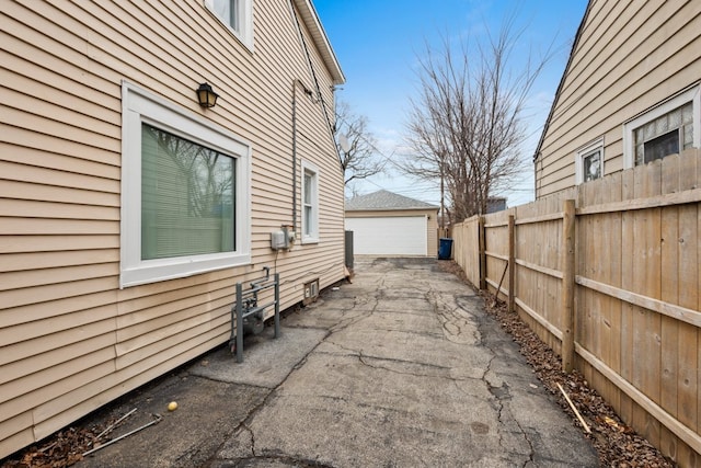 view of side of home featuring a garage, an outdoor structure, and fence