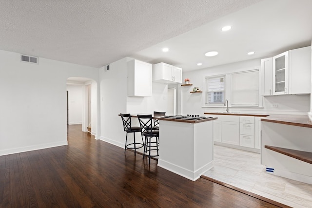 kitchen with open shelves, visible vents, arched walkways, and a sink