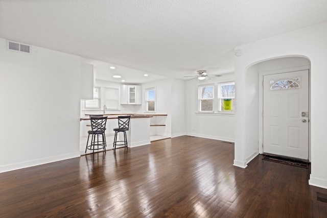 unfurnished living room with dark wood-style floors, a textured ceiling, visible vents, and baseboards